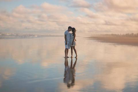 photo-of-couple-standing-on-water-with sky reflecting on sand