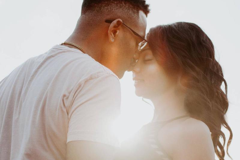 couple embrace at the beach with the sunlight coming through between them