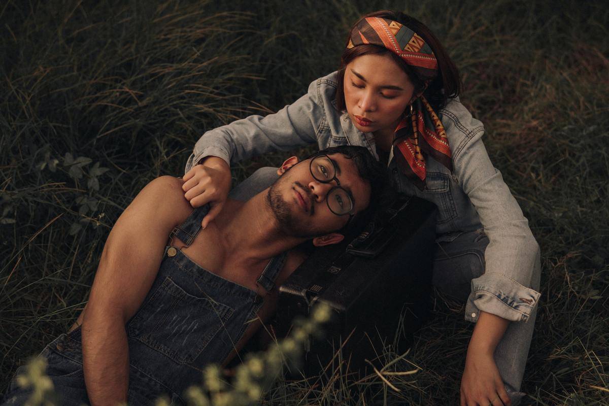 /couple-relaxing-on-grassland- with man laying on woman's lap