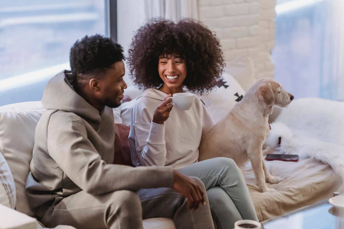loving-black-couple-communicating-while-sitting-on-sofa-with-adorable-dog-