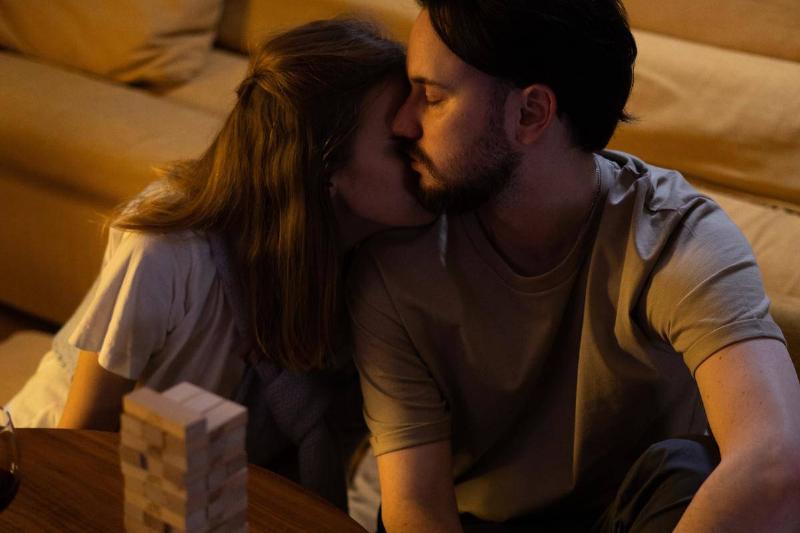 woman rests her chin on man's shoulder as they sit on the floor playing jenga