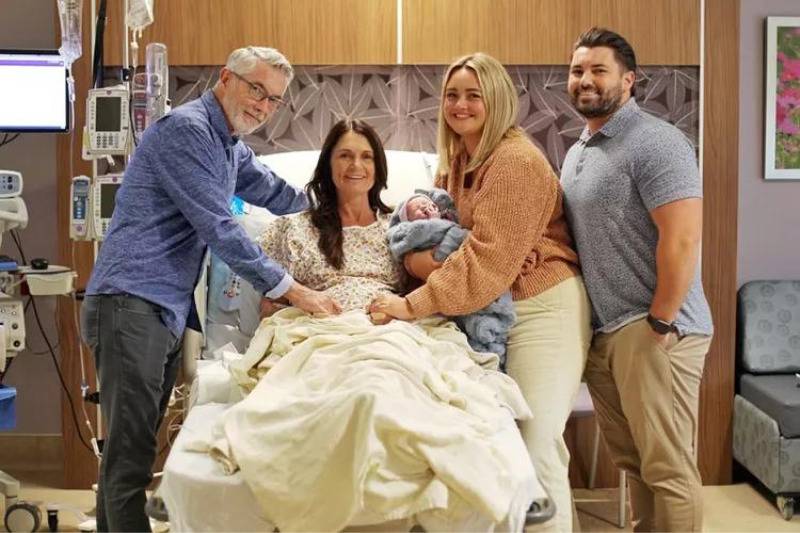 family at hospital bed smiling with baby
