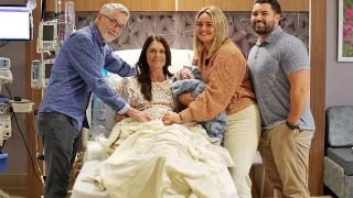 family at hospital bed smiling with baby