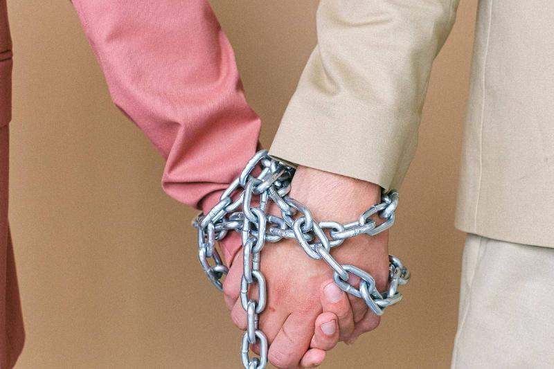 couple holds hands that are chained
