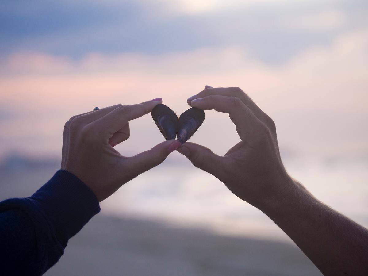 hand splitting heart apart in purple sky