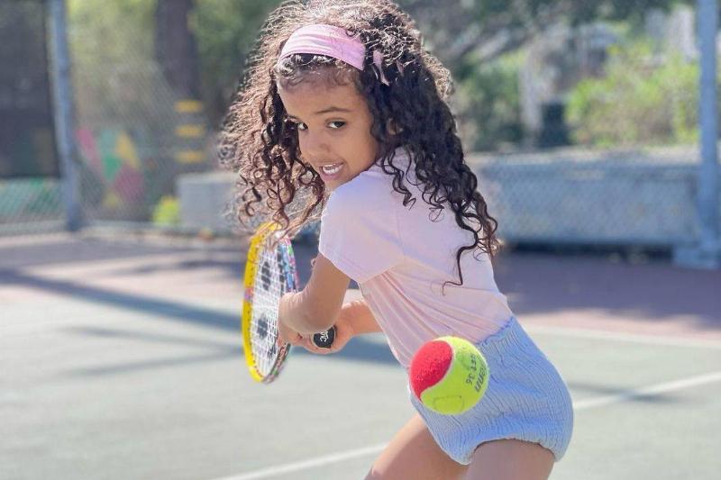 little girl playing tennis with racket