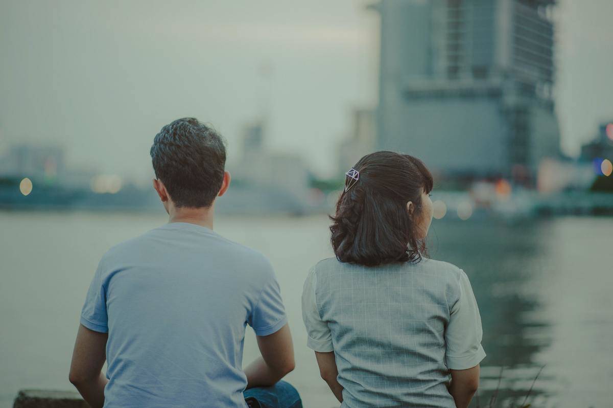 elective-focus-photography-of-man-and-woman-watching-body-of-water-and-concrete-buildings-