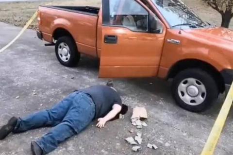 man plays dead by orange car