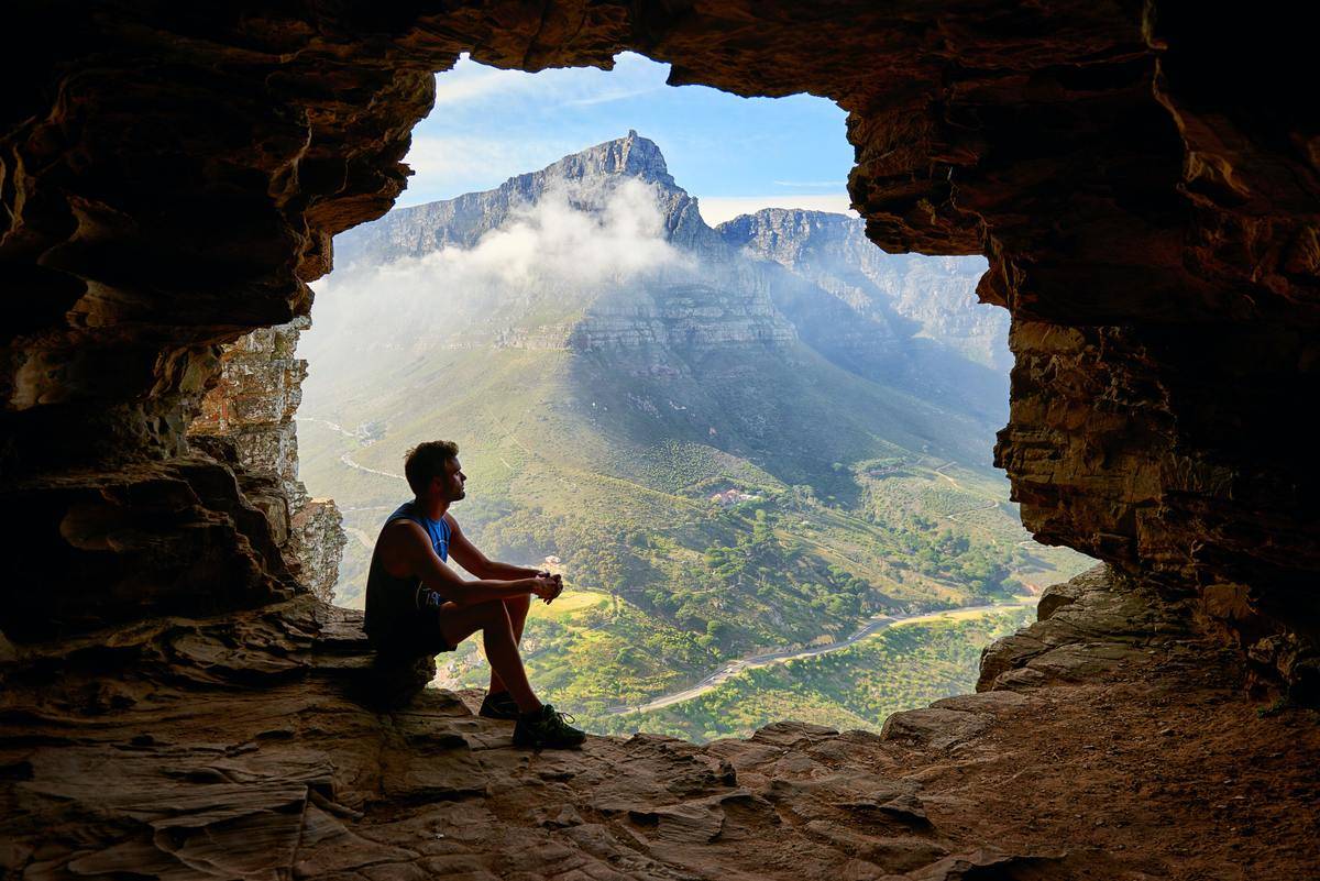 photo-of-man-sitting-on-a-cave