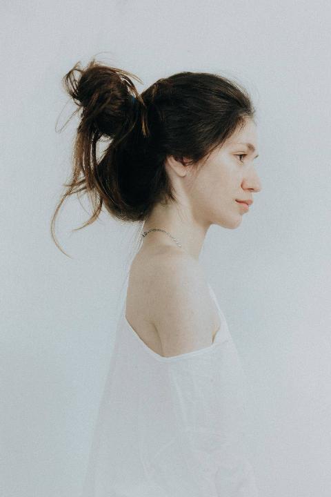 a-side-view-of-a-woman-in-white-off-shoulder-top-and messy bun