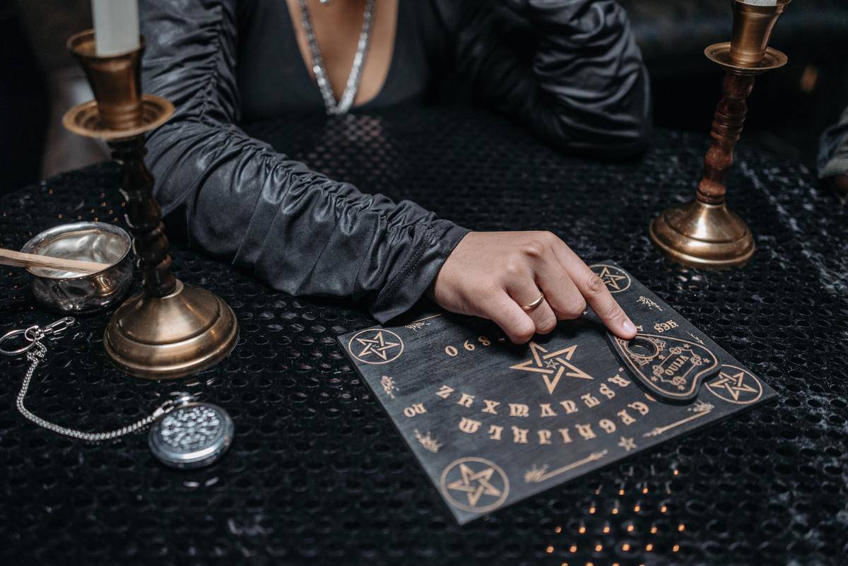 woman-in-black-long-sleeves-using-an-ouija-board-