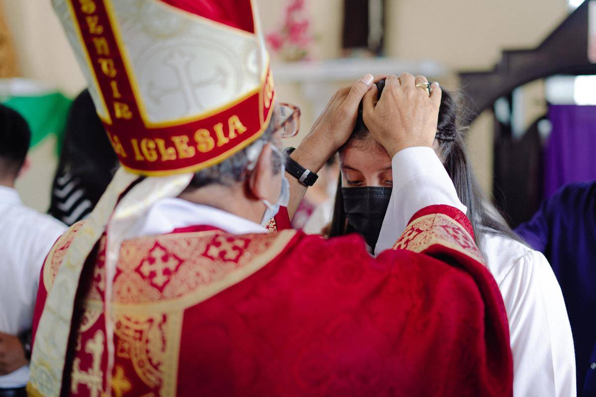 priest-during-a-ceremony putting his hands on a woman's head