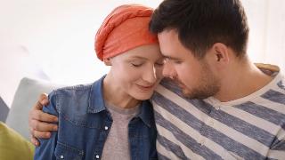 sick woman wearing head wrap comforted by man