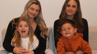 two besties holding their kids sitting on the couch