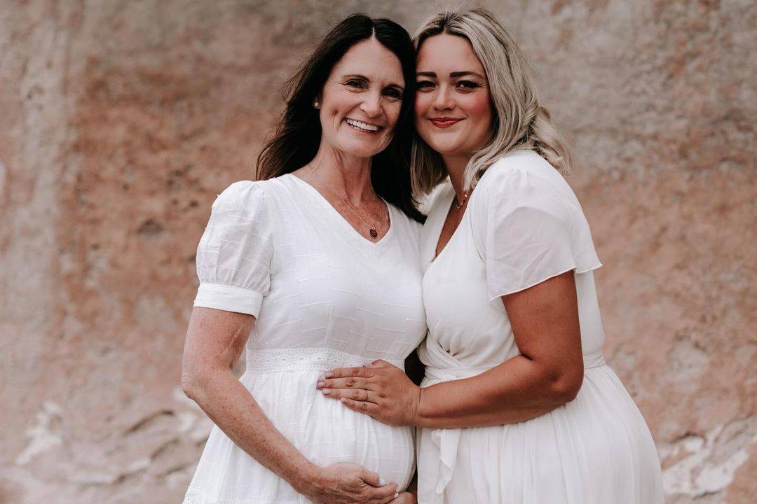 woman and daughter in law in white dresses smile in photoshoot