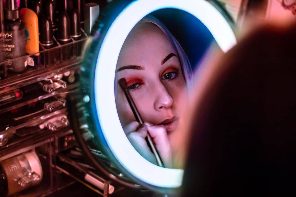 woman-facing-mirror-applying-eyeshadow