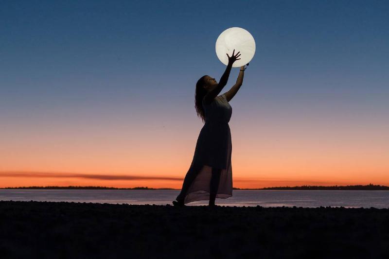 woman-holding-a-moon on the beach at sunset