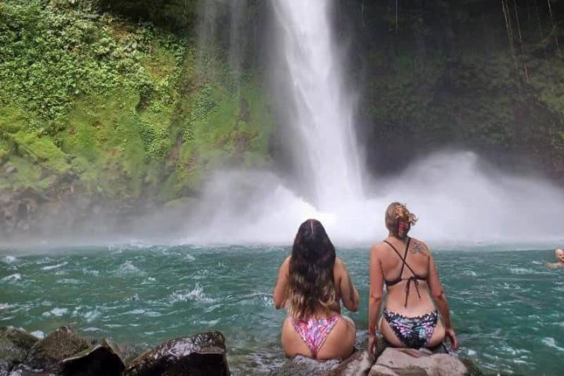woman sitting at waterfall in bathing suits