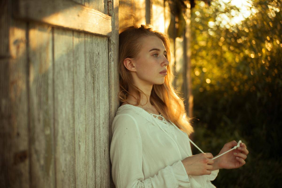 woman-wearing-white-top-leaning-on-wooden-wall-