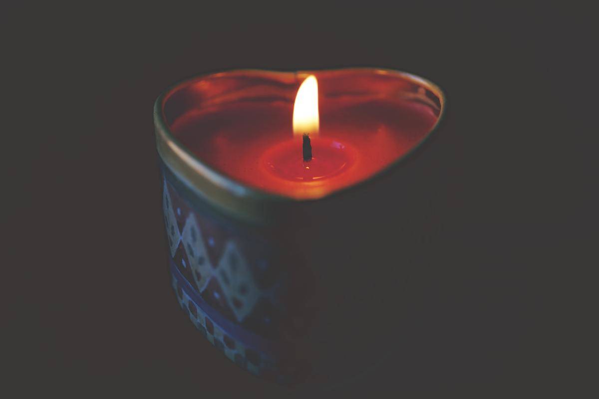 A red, heart-shaped candle burning.