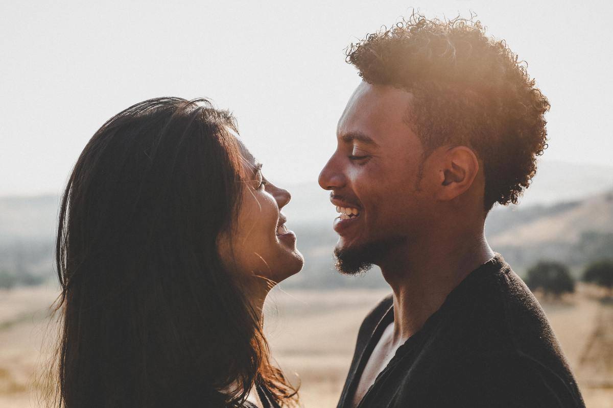 A man and a woman smiling at each other while standing close.