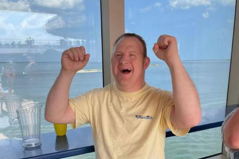 Dennis Peek in a yellow t-shirt on a boat, cheering.