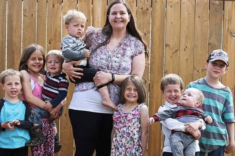 Mom and her 8 kids stand in backyard smiling