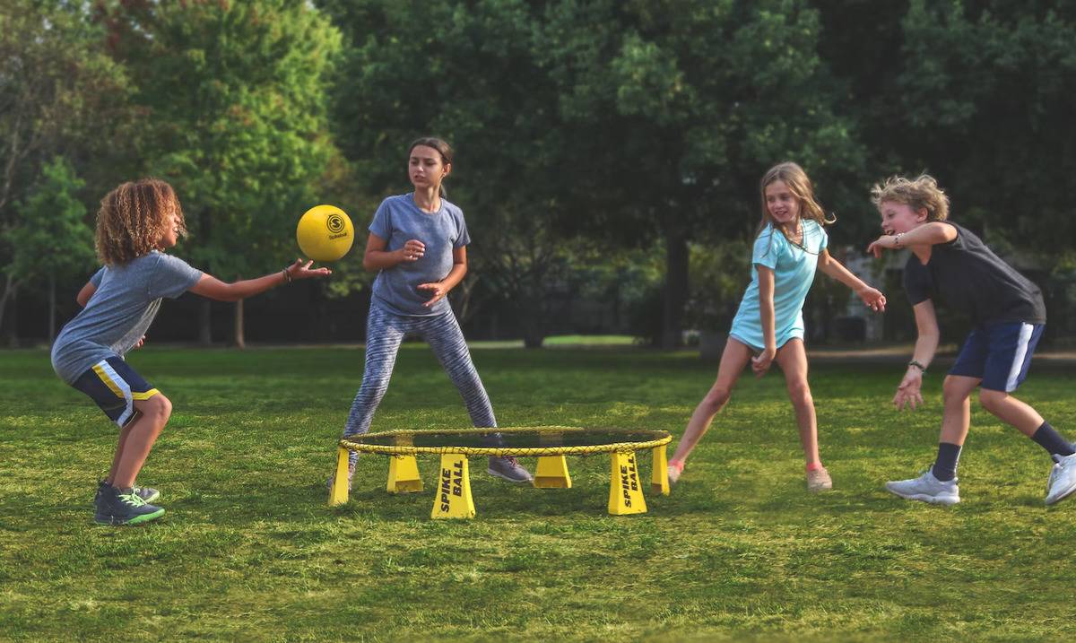 A group of kids playing spikeball outside.