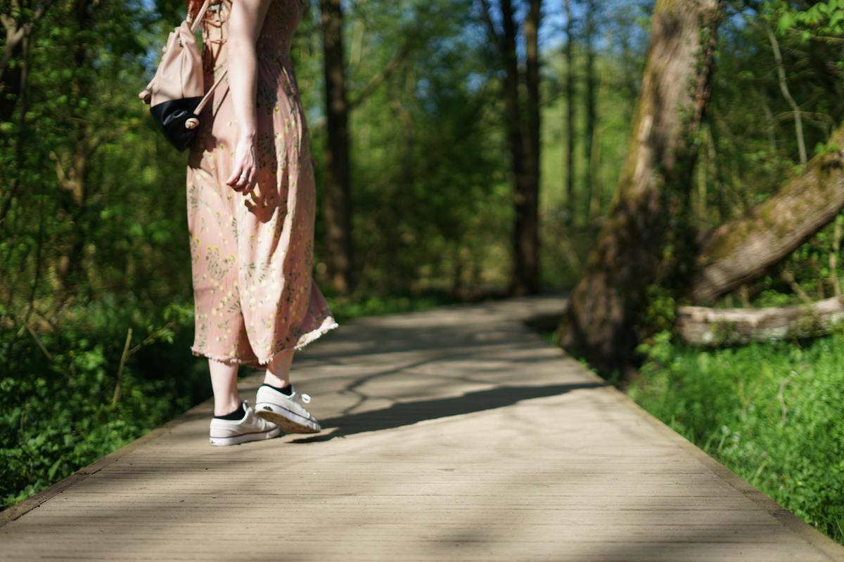 A woman walking along a boardwalk trail in a forest.
