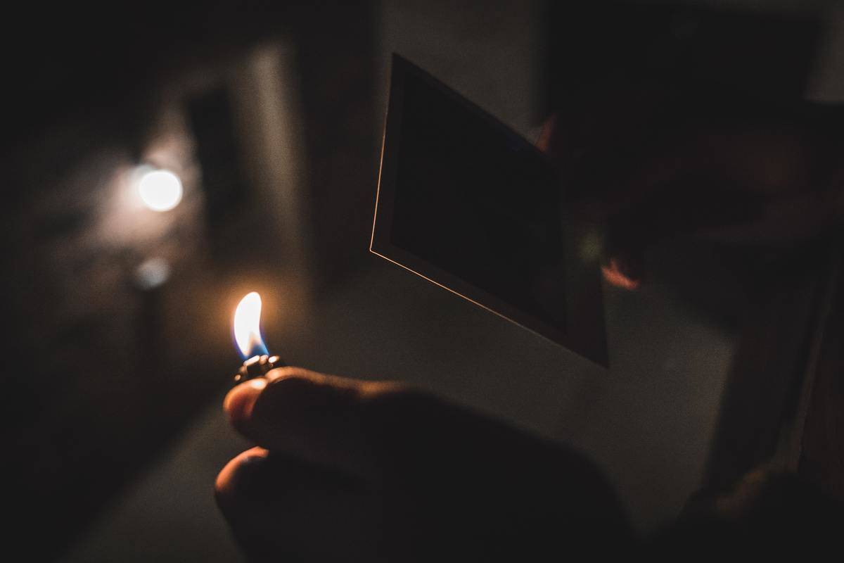 Someone holding a lighter up to a polaroid picture.