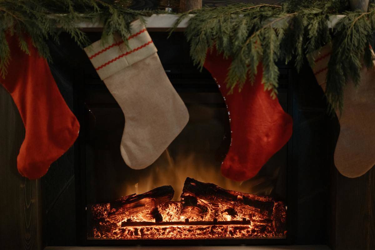 A lit fireplace with red and white stockings hanging in front of it.