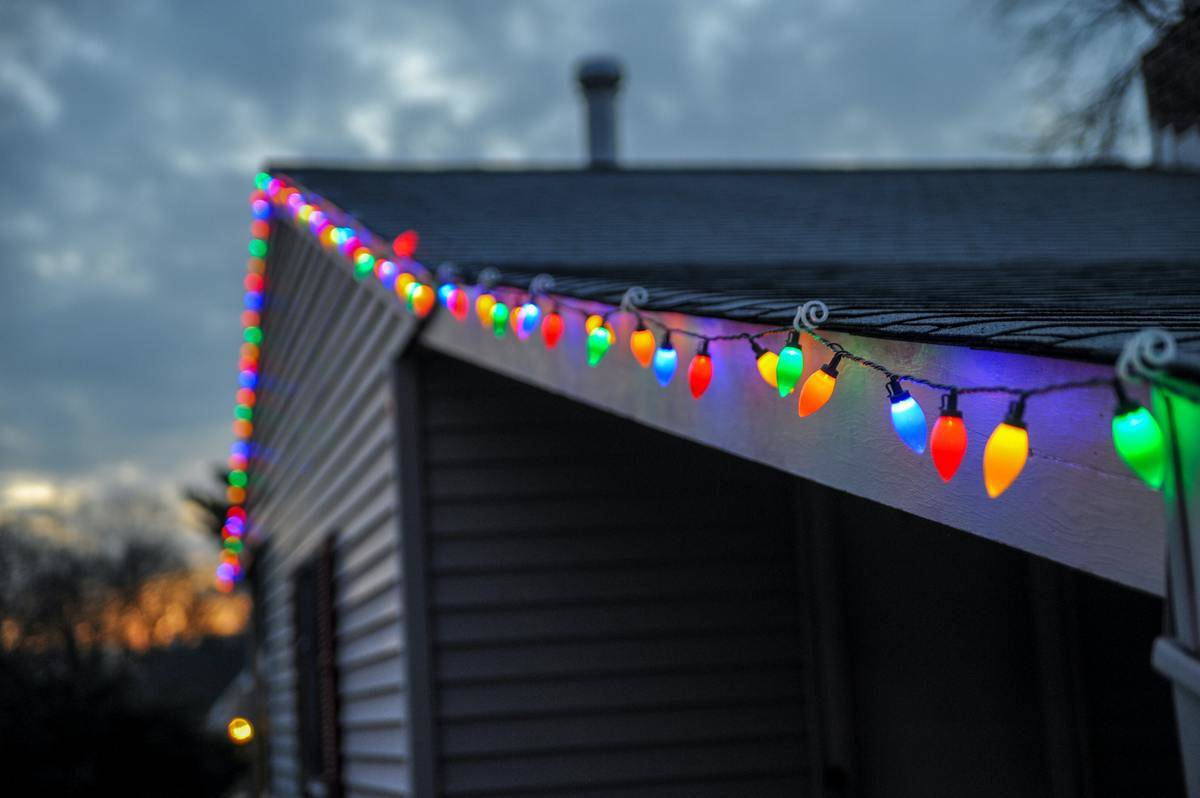 A string of multi-colored Christmas lights strung along the roof of a house.