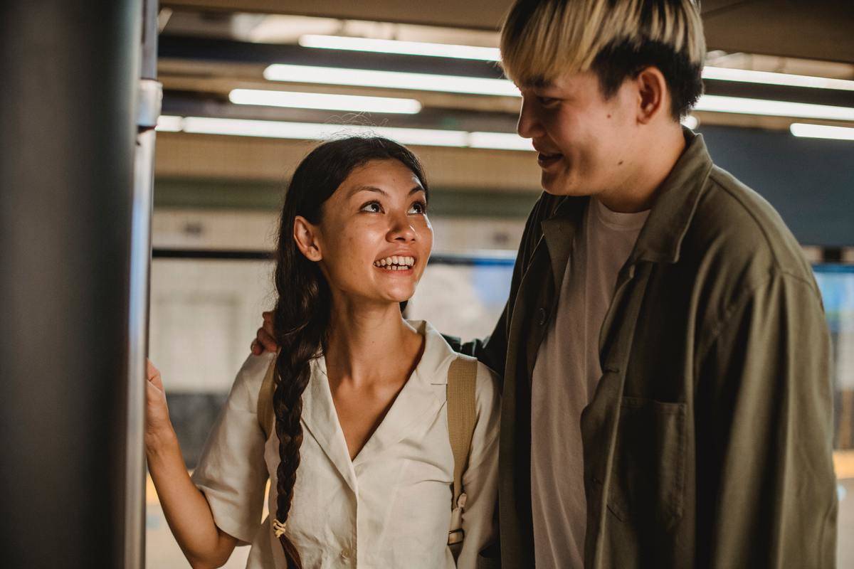 cheerful-asian-couple-standing-in-underground-station talking
