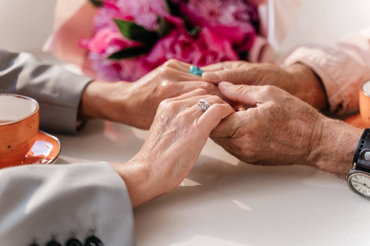 A closeup of an elderly couple holding hands.