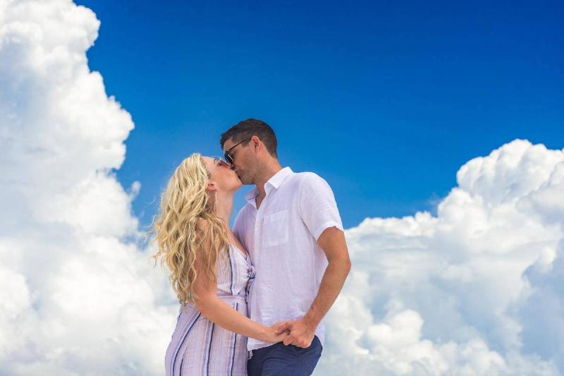man-and-woman-kissing-and-holding-hands-under the clouds