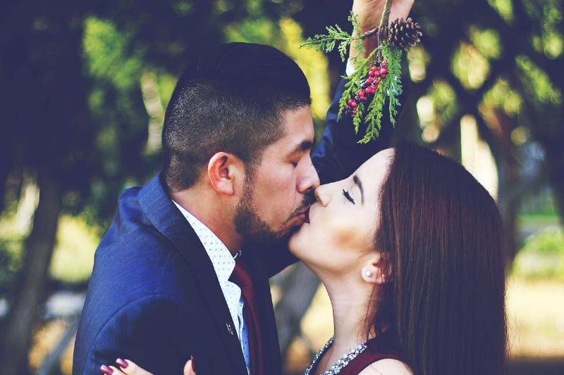 couple kiss under mistletoe dressed up