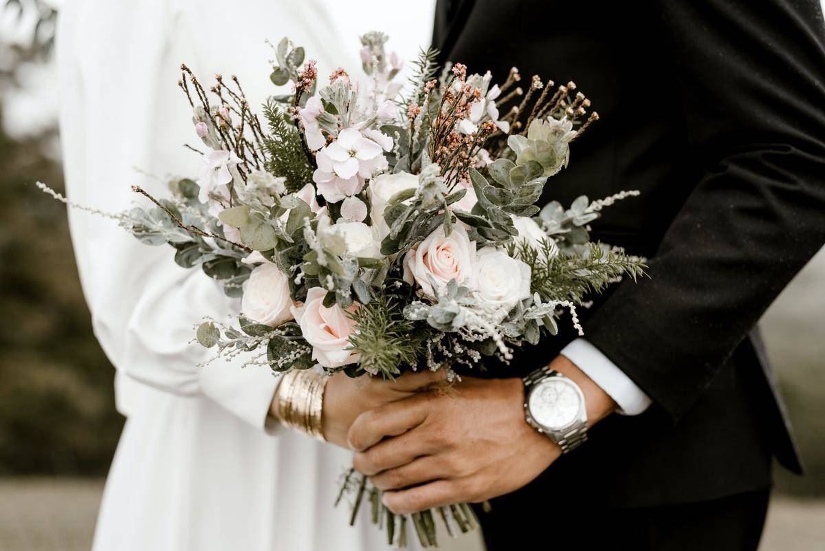 A closeup of a couple both holding a wedding bouquet.