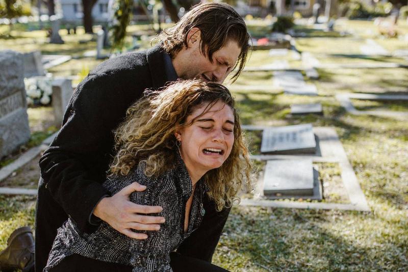 woman-crying-beside-a-man-in-a-cemetery