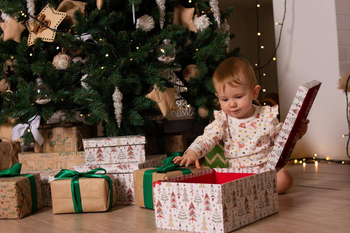 A toddler opening up a Christmas present.