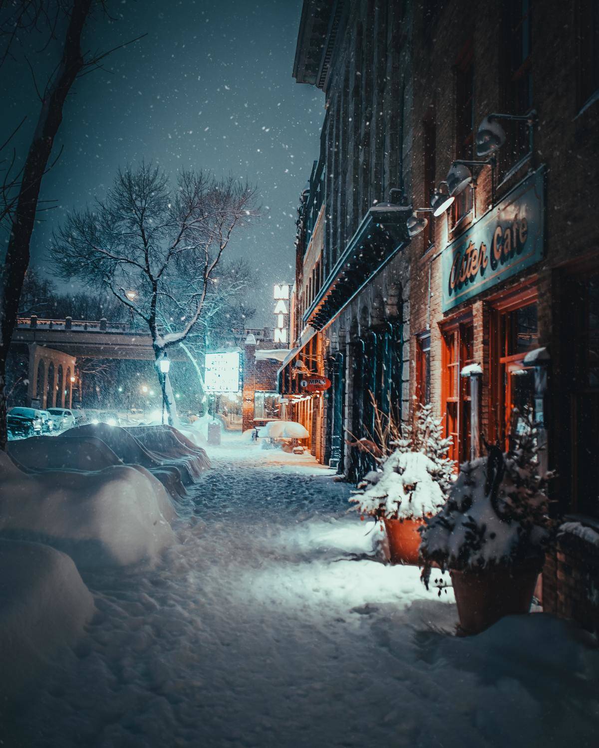 A snowy town street lit up at night.
