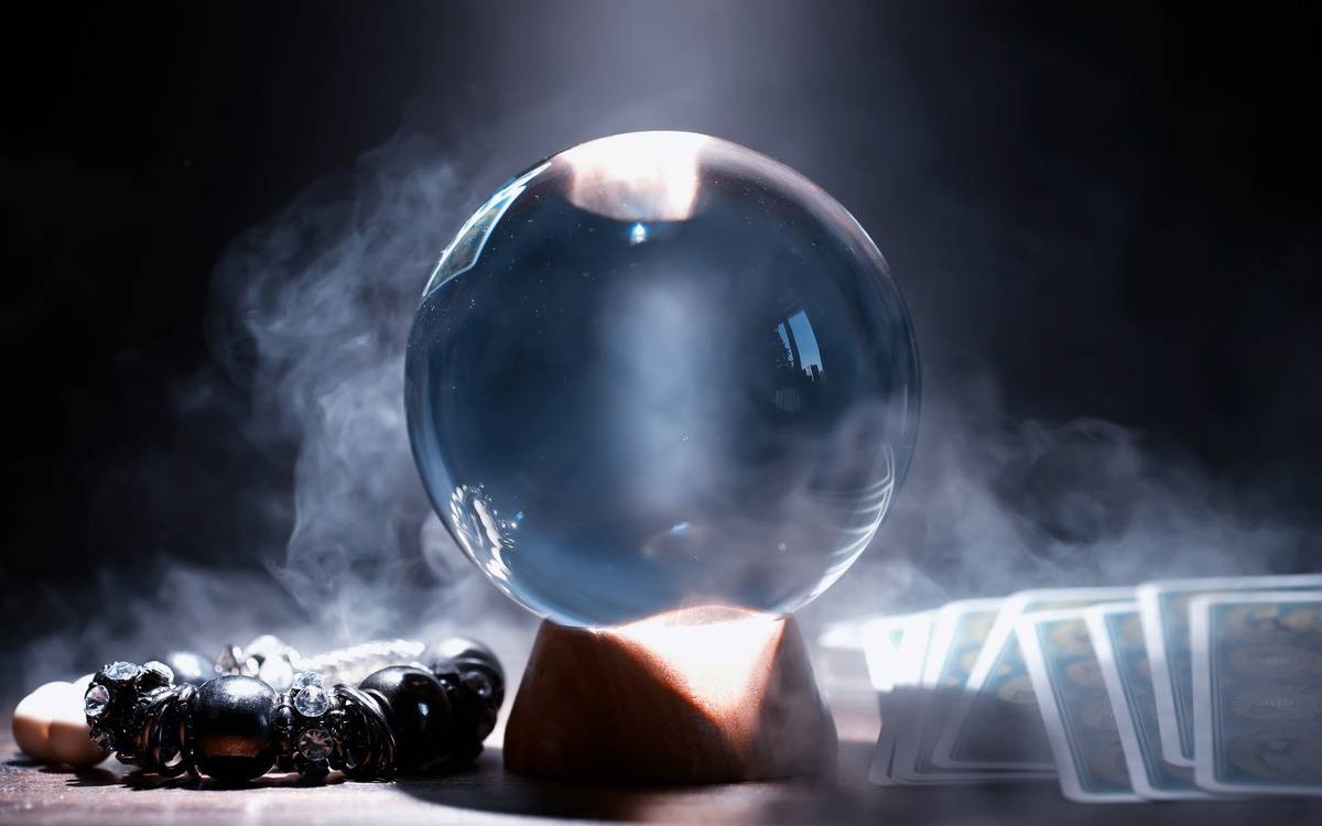 A crystal ball on a table with smoke behind it.