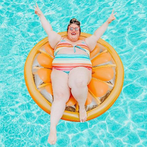 fran in pool on an orange floatie with arms up