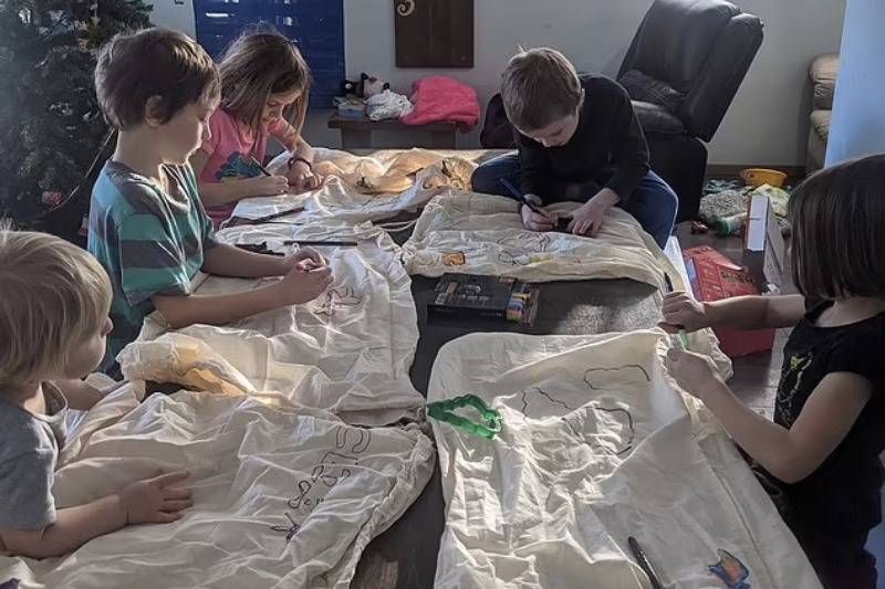 kids draw on sheets by chirstmas tree