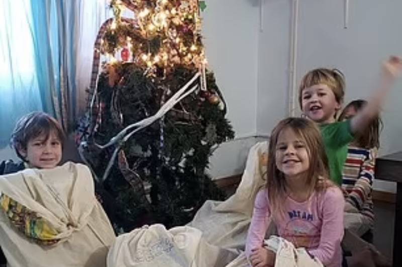 kids open christmas presents by tree