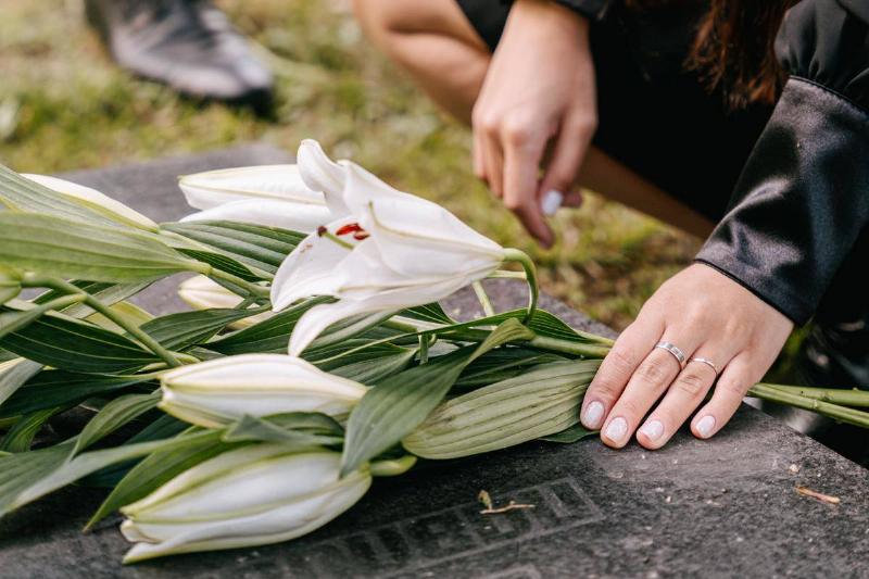 Someone laying a bouquet of flowers atop a gravestone.