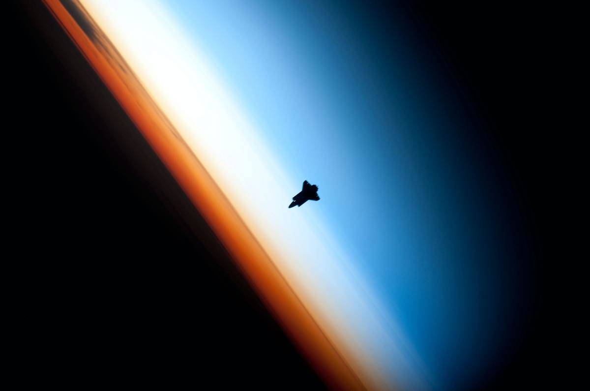A silhouette of a satellite orbiting a planet's atmosphere.