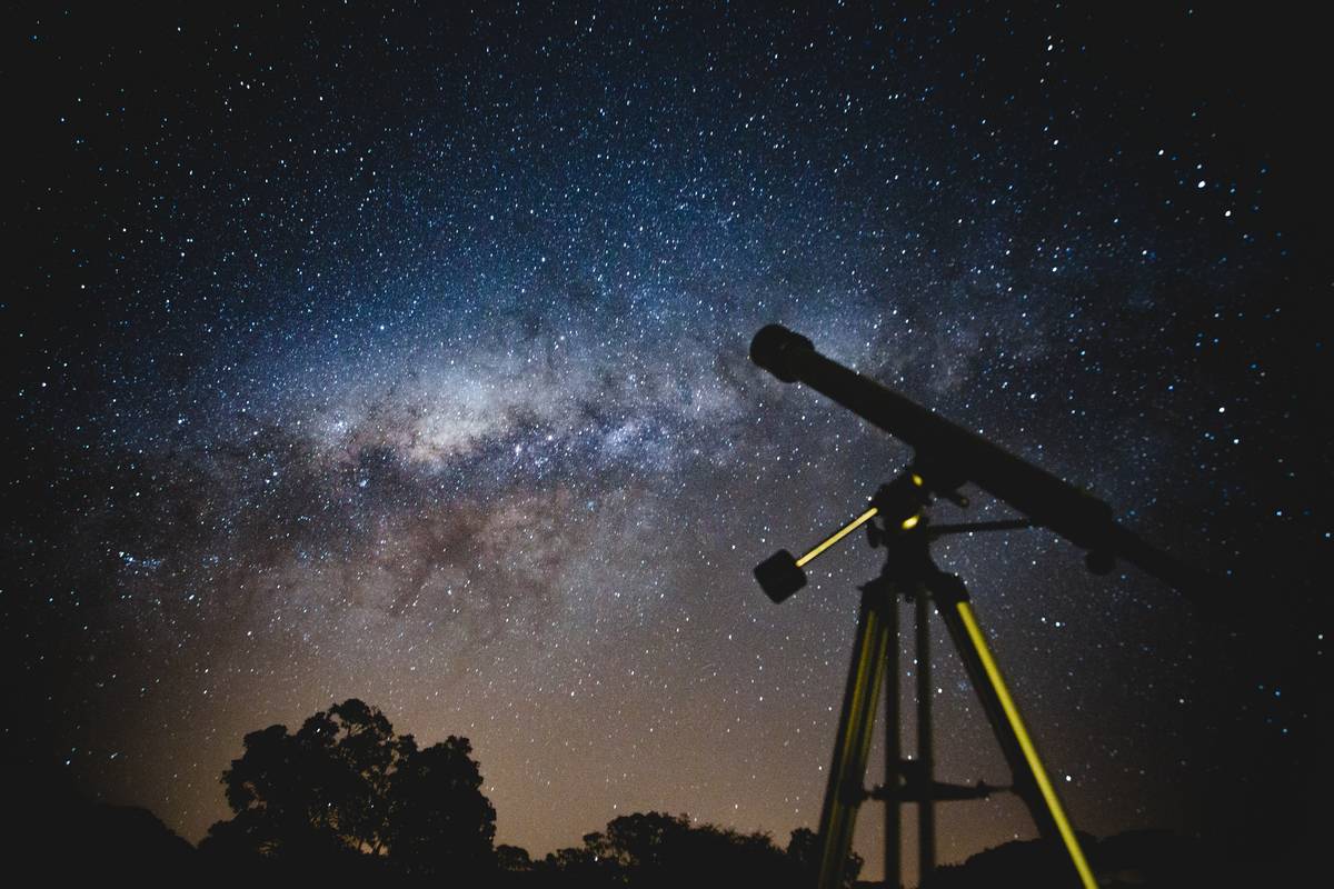 A telescope pointed up towards a star-filled night sky.