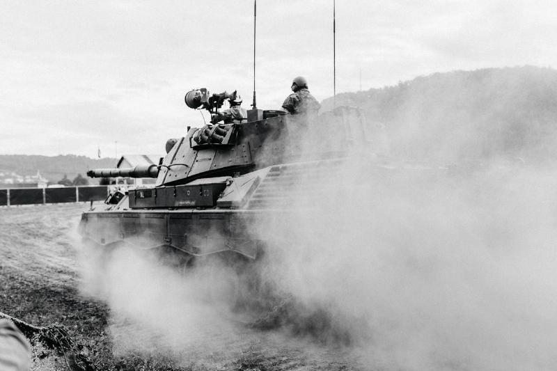 A greyscale image of men riding on a tank.