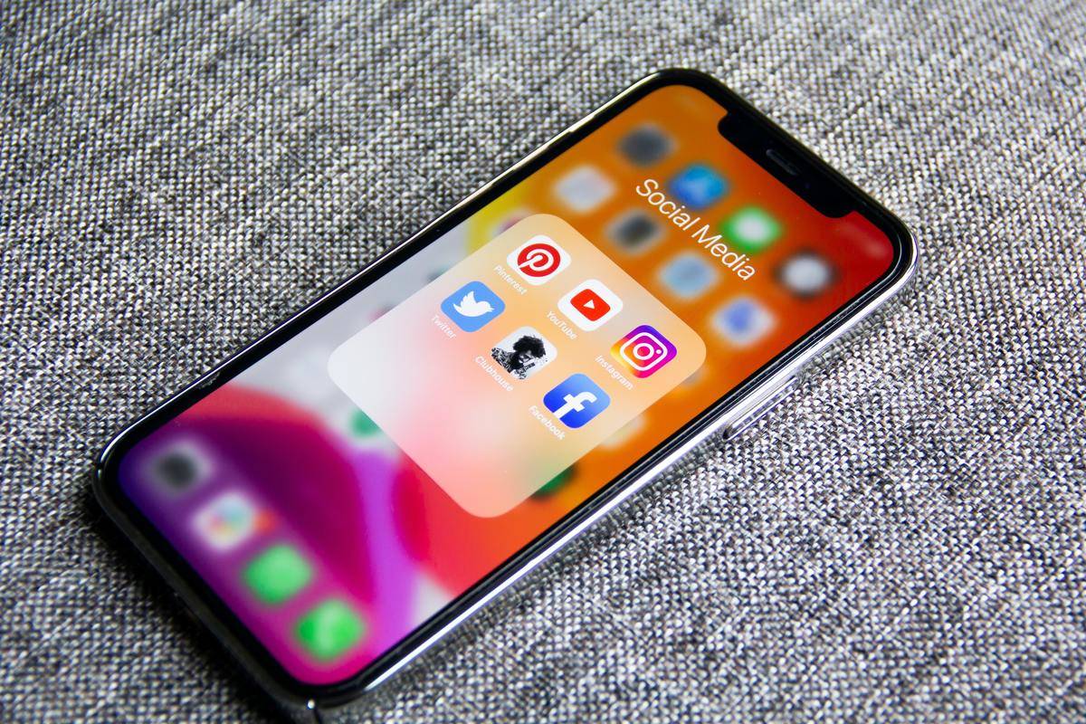An iPhone displaying a 'social media' folder containing popular social media apps.