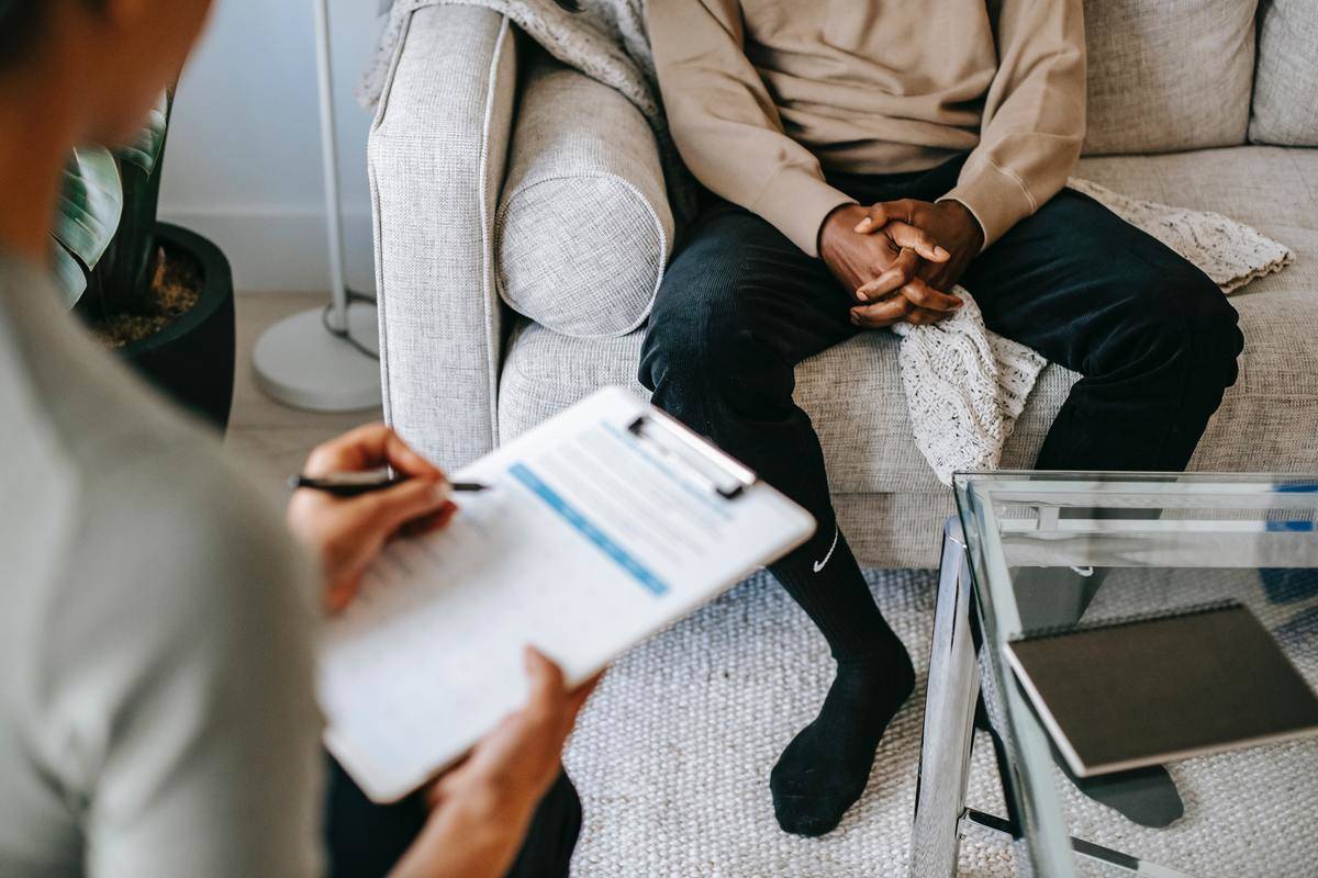 An over-the-shoulder shot of a therapist speaking to a patient.